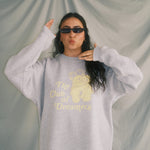 Person wearing a gray sweatshirt with a bear graphic and text, standing against a plain background.