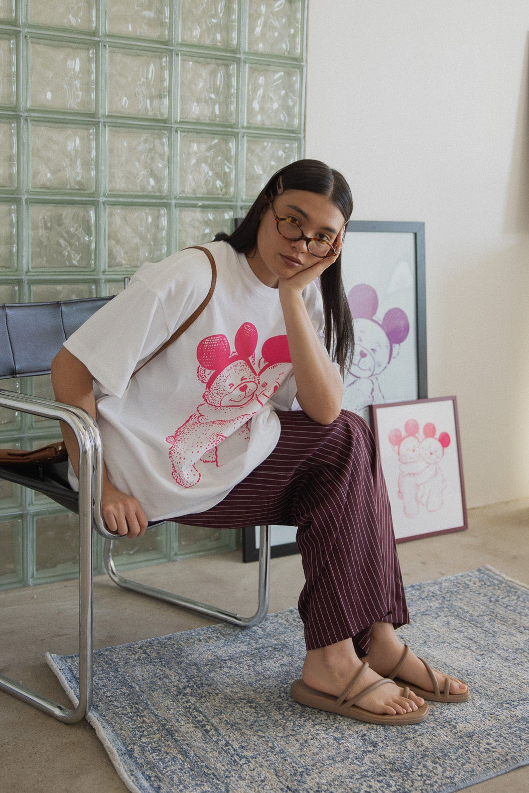 Woman sitting on a chair in a room with glass block wall and framed pictures.