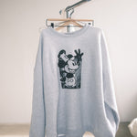 Gray sweatshirt with a graphic design on a hanger against a plain background