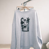 Gray sweatshirt with a graphic design on a hanger against a plain background