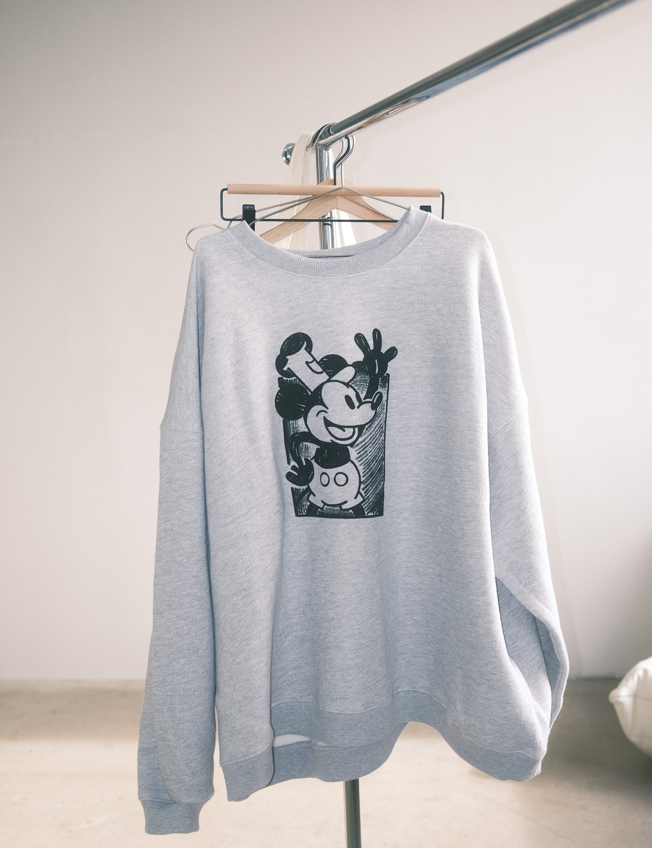Gray sweatshirt with a graphic design on a hanger against a plain background