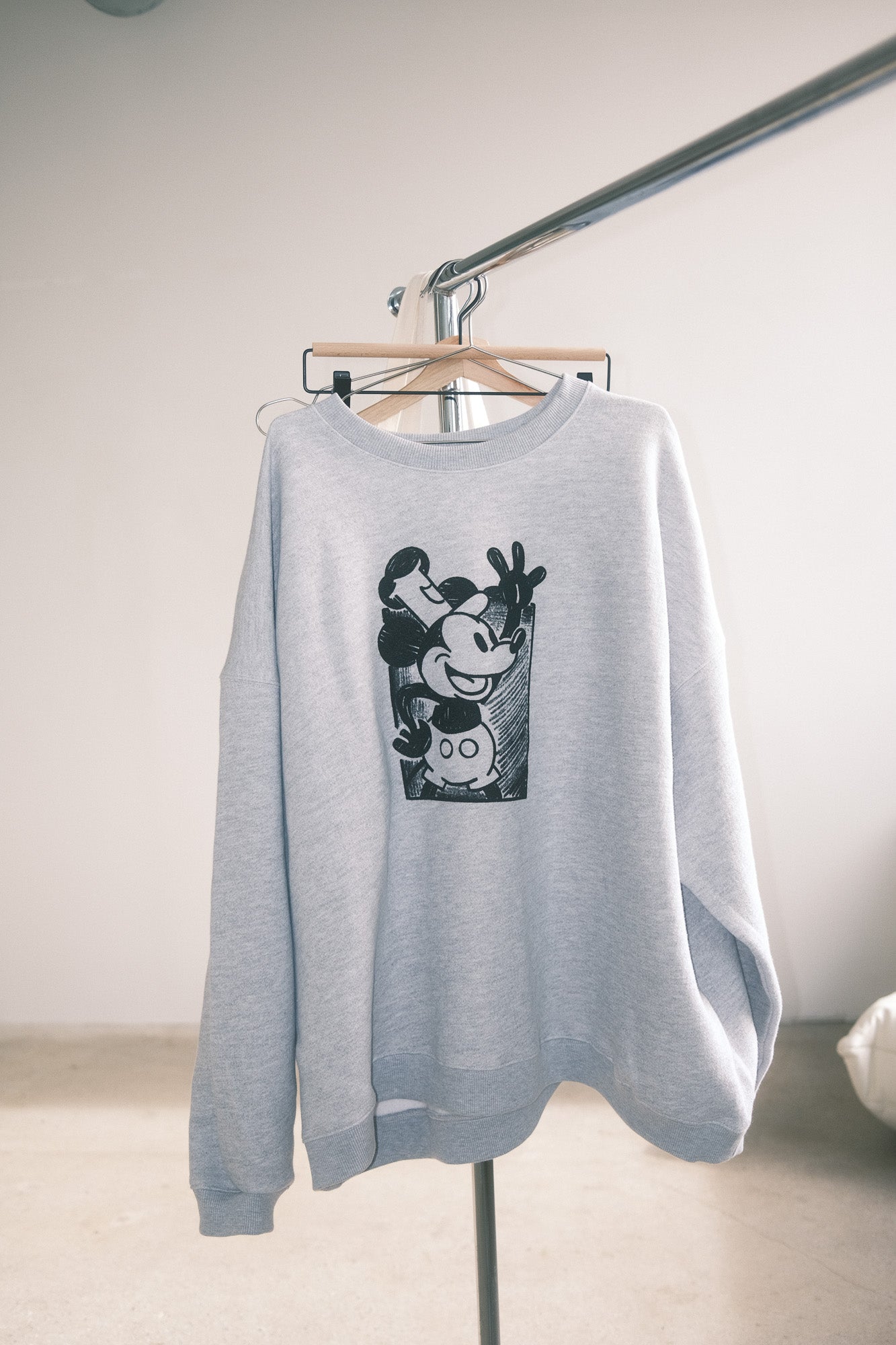 Gray sweatshirt with a graphic design on a hanger against a plain background