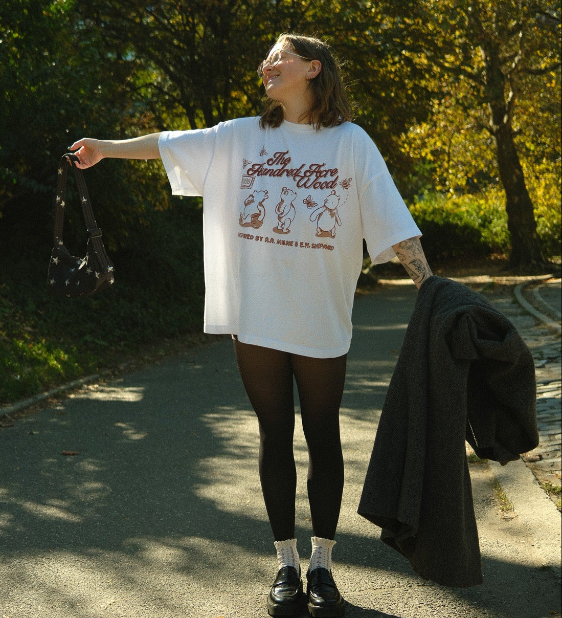 Person standing outdoors in a park with trees and sunlight