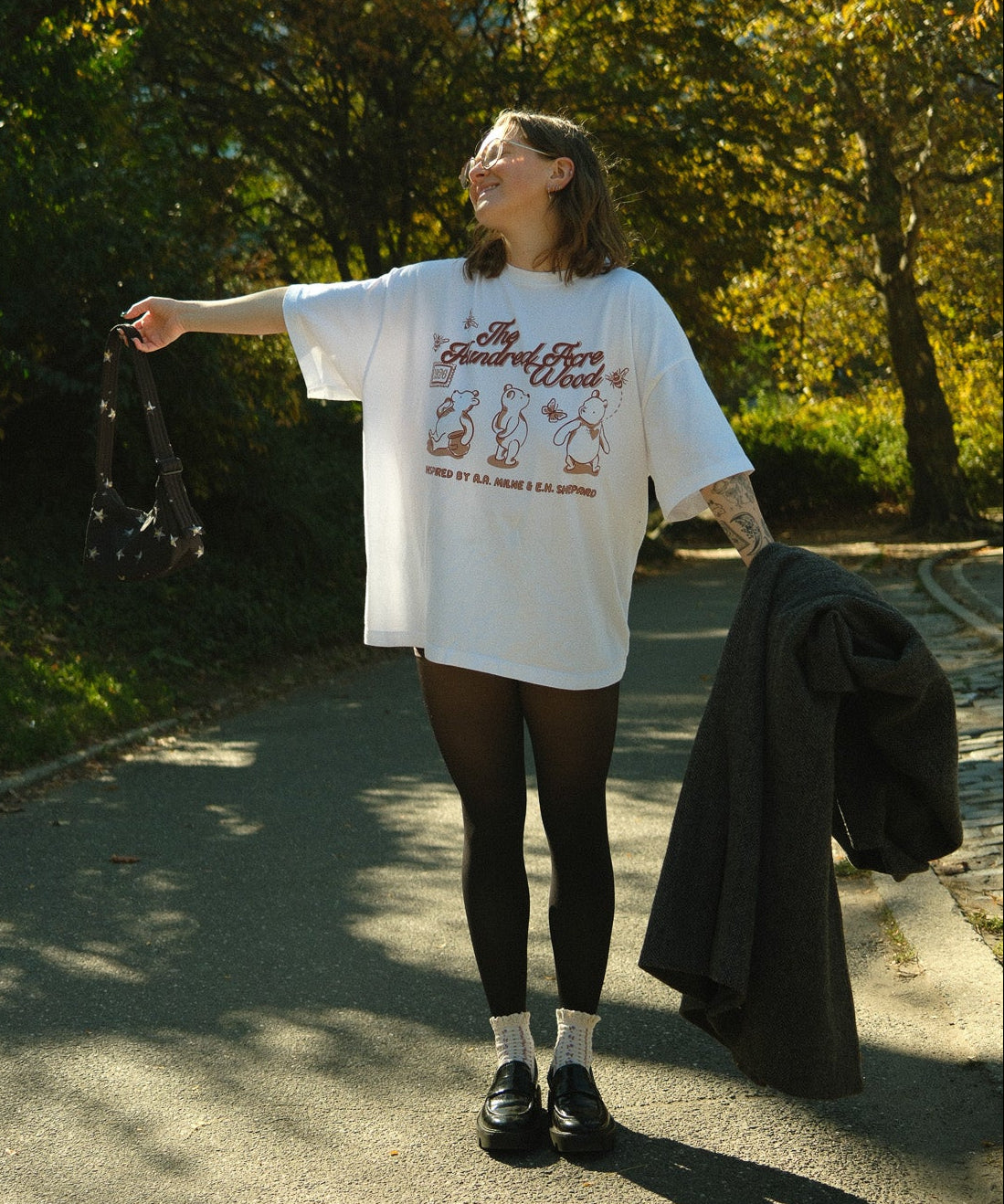 Person standing outdoors in a park with trees and sunlight