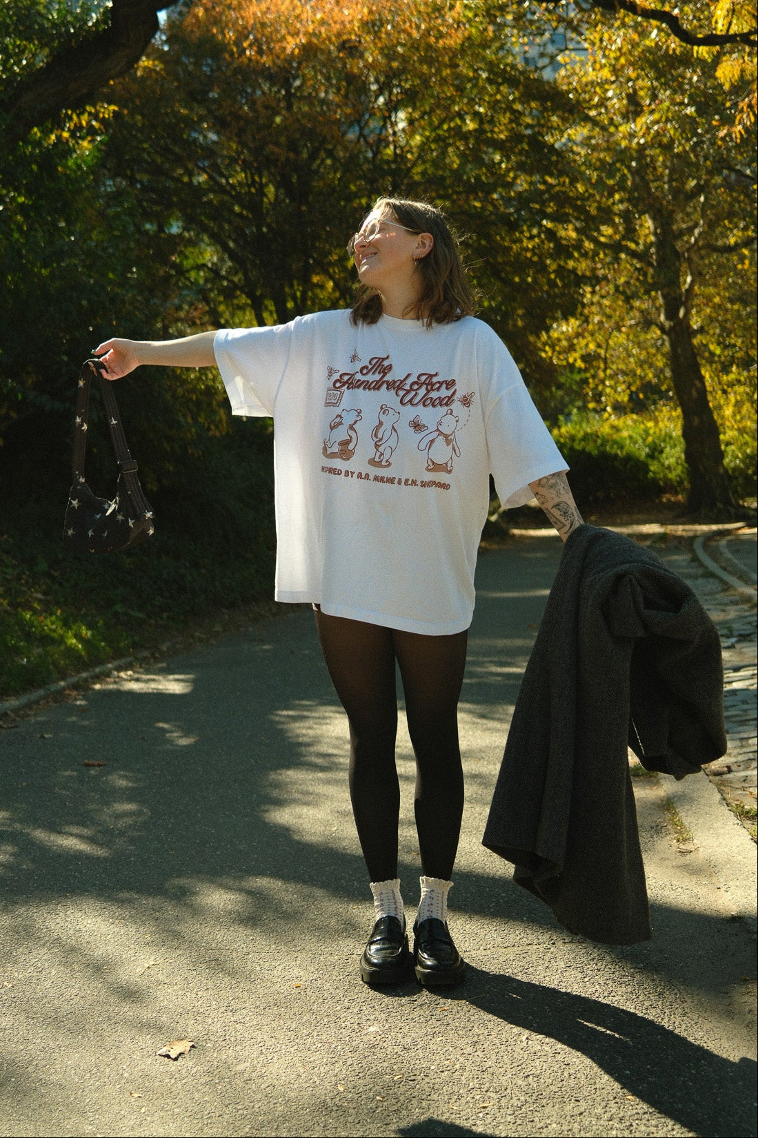 Person standing outdoors in a park with trees and sunlight